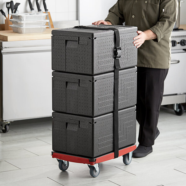 A man pushing a cart with a stack of black CaterGator pan carriers.