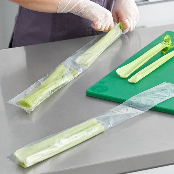 A woman wearing gloves cutting celery on a cutting board and placing it in a Choice clear polyethylene layflat bag.