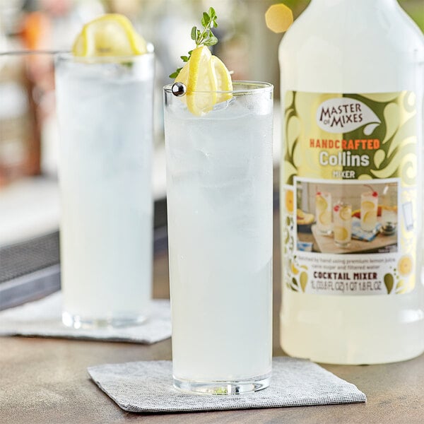 A glass of Master of Mixes Tom Collins with lemon slices and a lemon wedge.