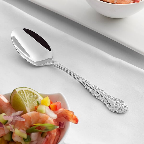 An Acopa stainless steel teaspoon in a bowl of shrimp.