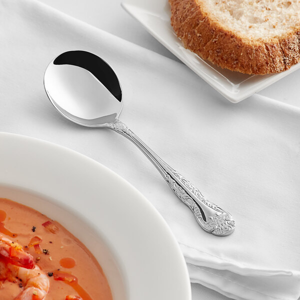 An Acopa Capulet stainless steel bouillon spoon in a bowl of soup.