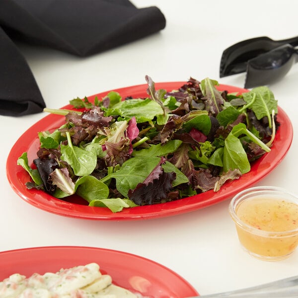 A red Carlisle Kingline oval platter with salad on it.