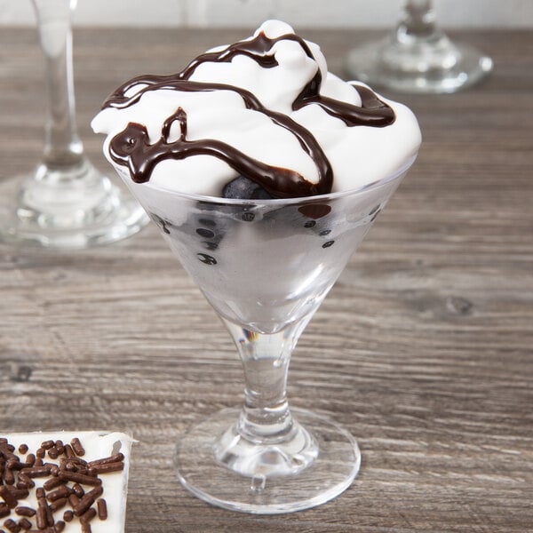 A GET SAN plastic martini glass with ice cream and chocolate drizzle on top.