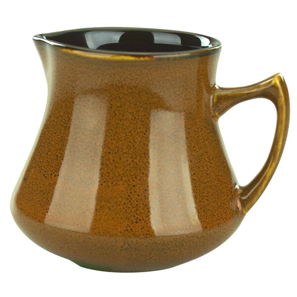 A brown pitcher with a black handle.