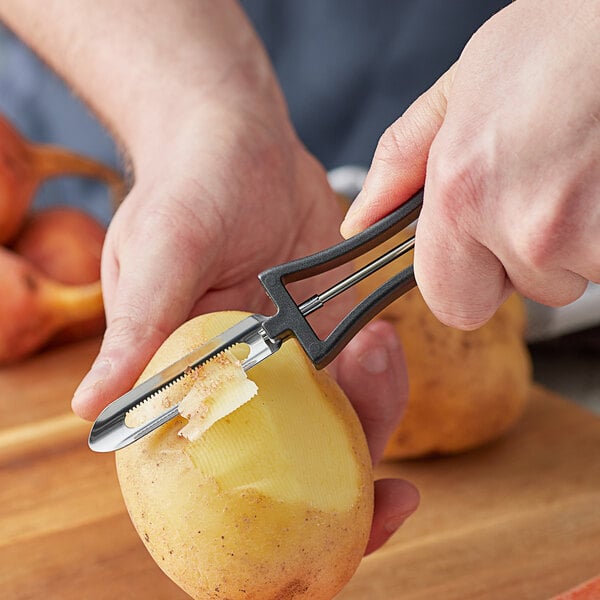 A person using the Choice 6" floating vegetable peeler to peel a potato.