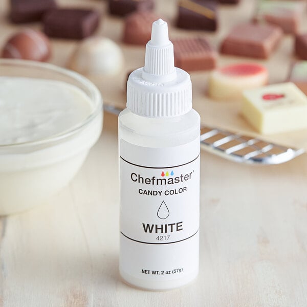A white bottle of Chefmaster White Oil-Based Candy Color with a white cap next to a bowl of white liquid.