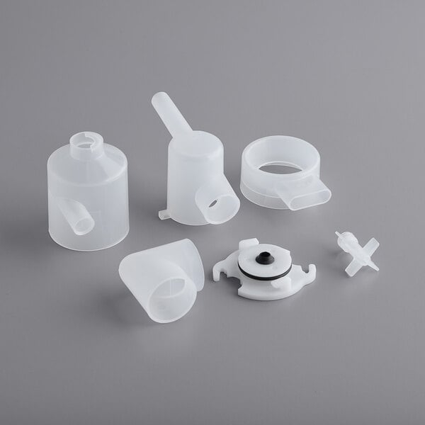 A group of white plastic parts including a tube and a white plastic object with a black ring.