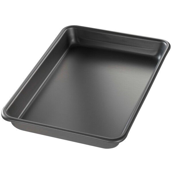 A black Chicago Metallic BAKALON aluminum sheet pan with a curled rim on a counter.