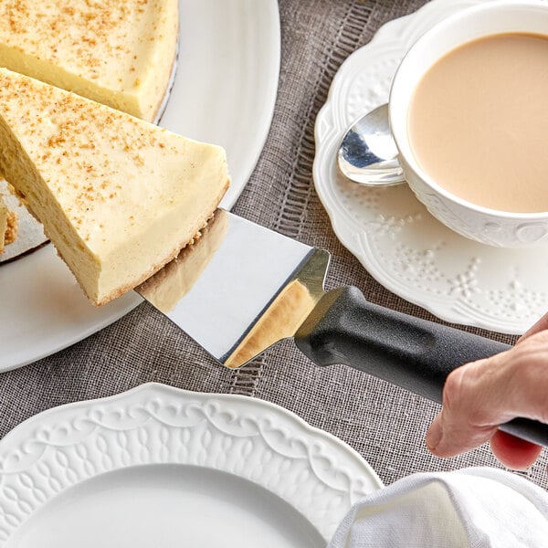 A person cutting a slice of cheesecake with a Choice pie server.