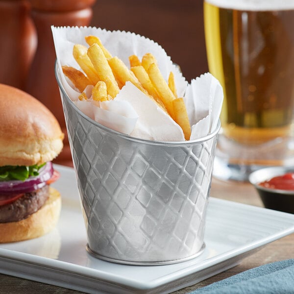 A Tablecraft lattice stainless steel fry cup filled with fries served with a burger.