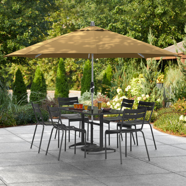 A Lancaster Table & Seating aluminum umbrella over a table and chairs on a patio.