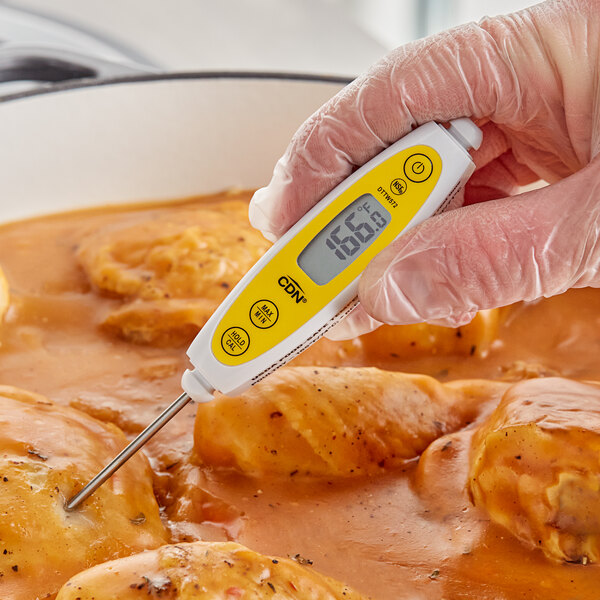 A hand holding a CDN ProAccurate digital pocket probe thermometer over food.
