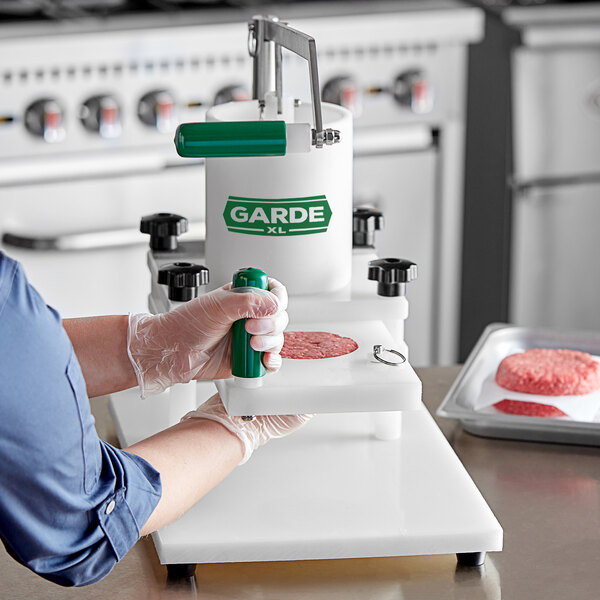 A woman using a Garde burger press to make a hamburger on a counter.