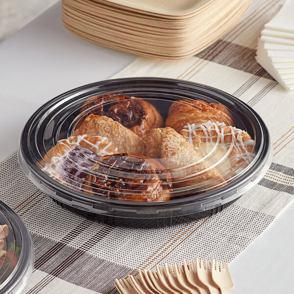 A Choice round catering tray with a plastic container of pastries on a table.