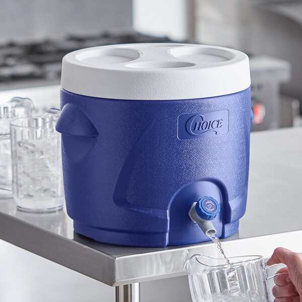 A person pouring water into a blue Choice insulated beverage dispenser.