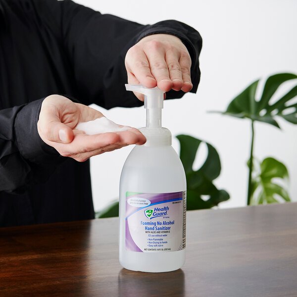A hand holding a Kutol Health Guard foaming hand sanitizer bottle.