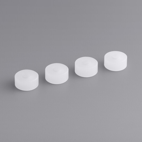 A row of white plastic caps with circular tops.