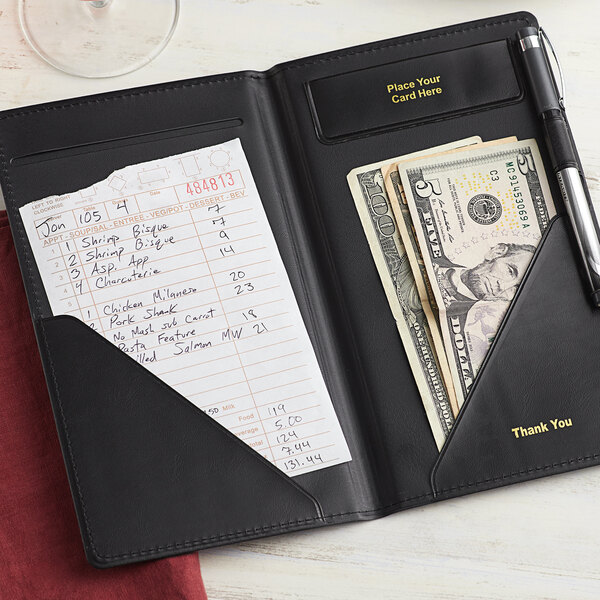 A black vinyl Choice guest check presenter on a counter with cash inside.