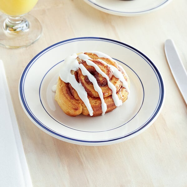 An Acopa stoneware plate with a cinnamon roll and orange juice on a table.