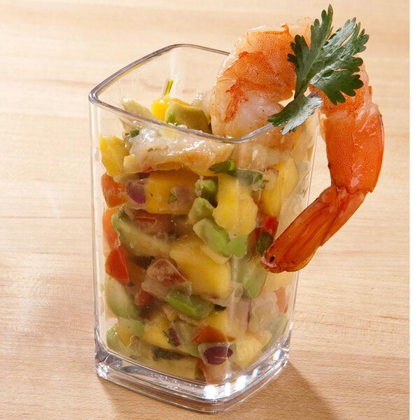 A Cambro plastic square dessert glass filled with shrimp, avocado, and vegetables.