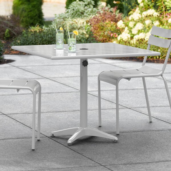 A white Lancaster Table & Seating outdoor table with two chairs on a patio.