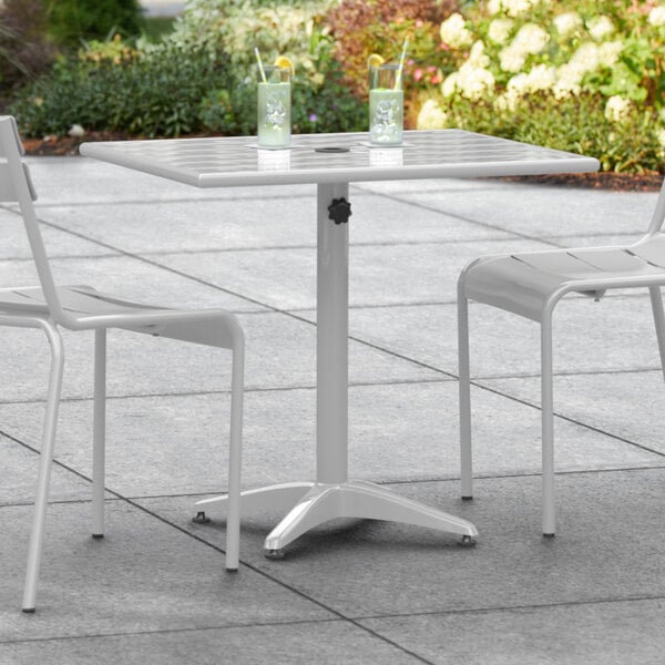 A Lancaster Table & Seating outdoor table with two chairs on a patio.