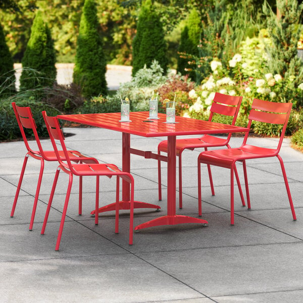 A Lancaster Table & Seating red aluminum dining table and chairs on a patio.