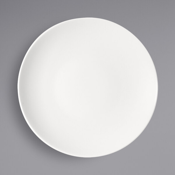 A Bauscher bright white porcelain half-deep coupe plate on a gray surface.