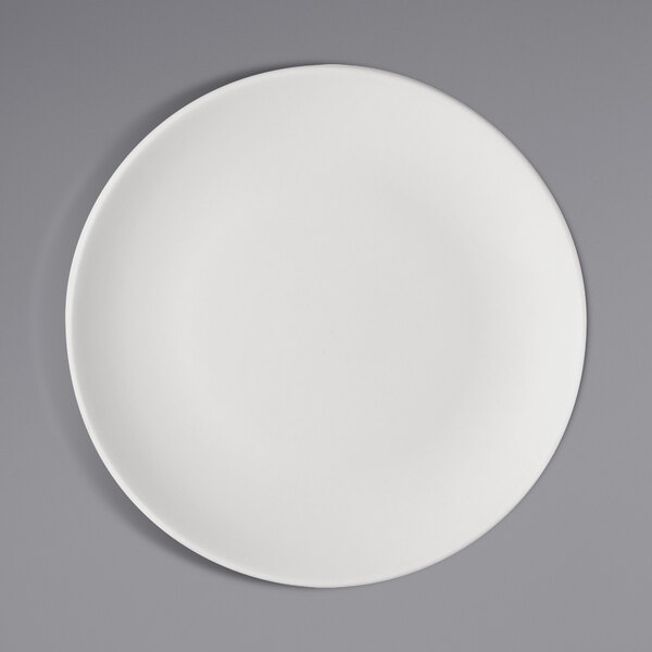 A Bauscher bright white porcelain coupe plate with a white rim on a gray surface.