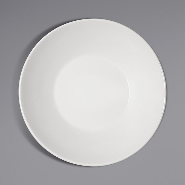 A Bauscher bright white porcelain deep coupe plate with a white rim on a gray surface.