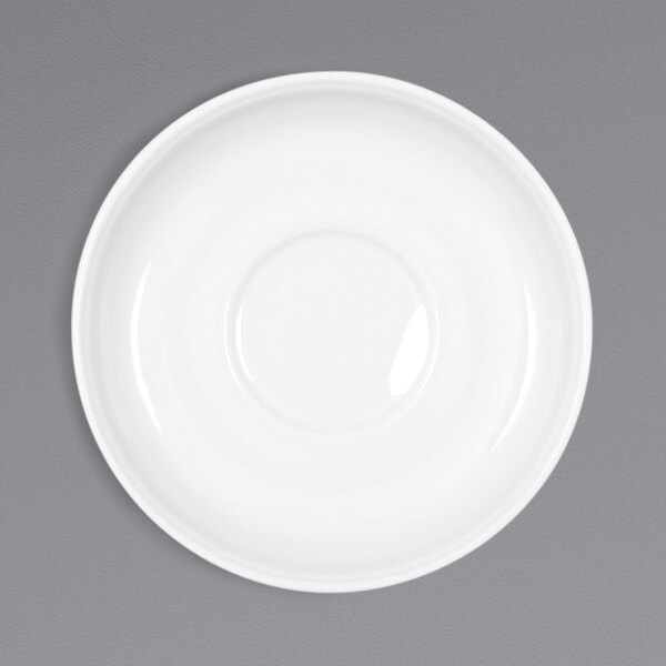 A Bauscher bright white porcelain saucer with a circular edge on a gray surface.