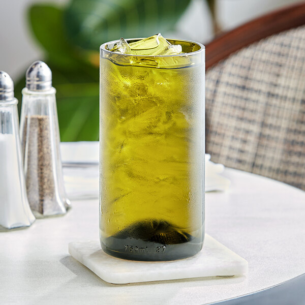 A Fortessa olive green wine tumbler filled with a green liquid and ice on a table.