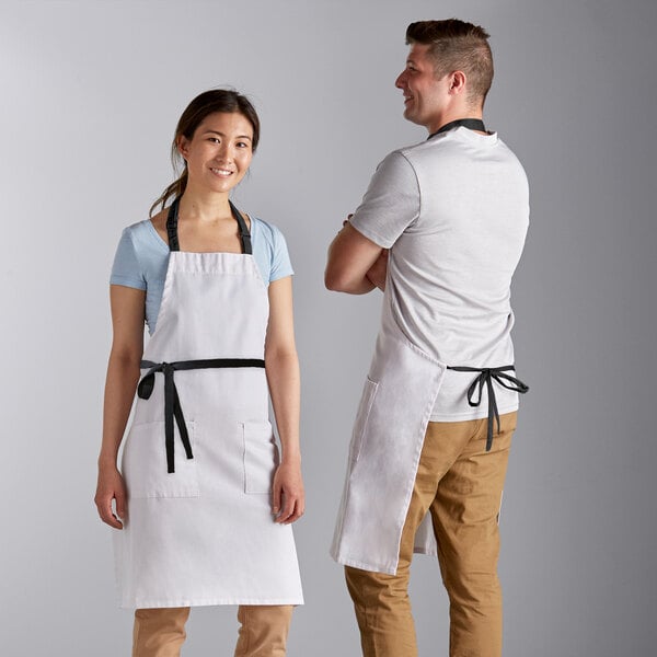 A man and woman wearing Choice white bib aprons with black webbing accents.