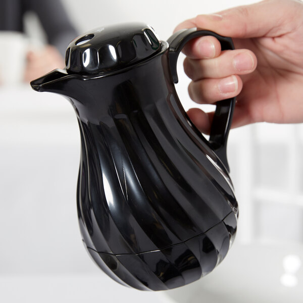 A hand holding a black Vollrath SwirlServe beverage server.