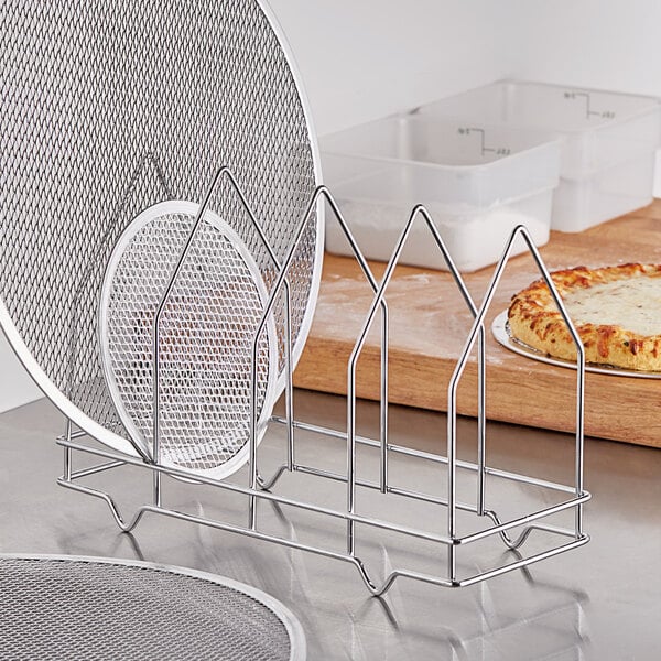 A metal Choice four-slot pizza screen rack holding several pizza pans.