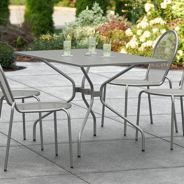 A Lancaster Table & Seating Harbor Gray rectangular outdoor table with chairs on a patio.