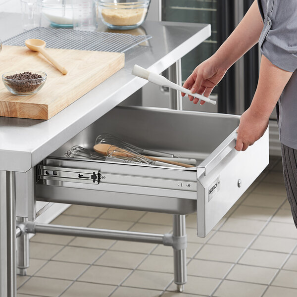 A person using utensils in a Regency Spec Line drawer in a professional kitchen.