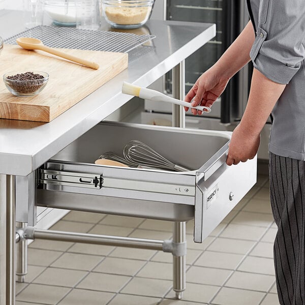 A person opening a Regency stainless steel drawer in a professional kitchen.