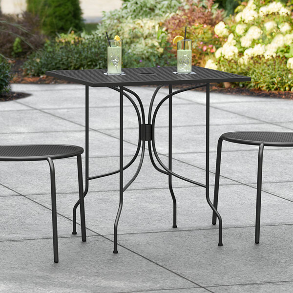 A Lancaster Table & Seating black rectangular outdoor table with two chairs on a patio.