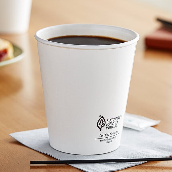 A Dart white paper hot cup of coffee on a table with a napkin.