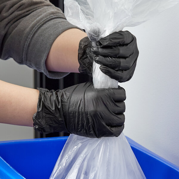 A person wearing Lavex black gloves holding a plastic bag.