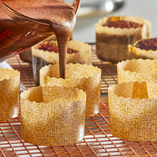 A person pouring brown liquid into a Novacart paper baking mold.