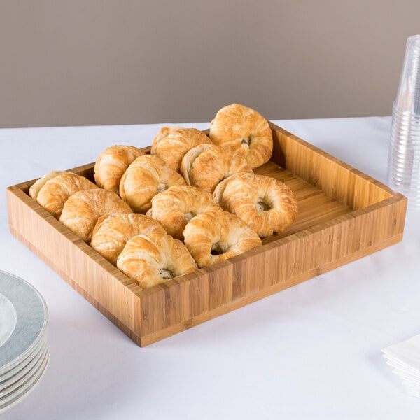 A Cal-Mil bamboo display tray with croissants on a table.