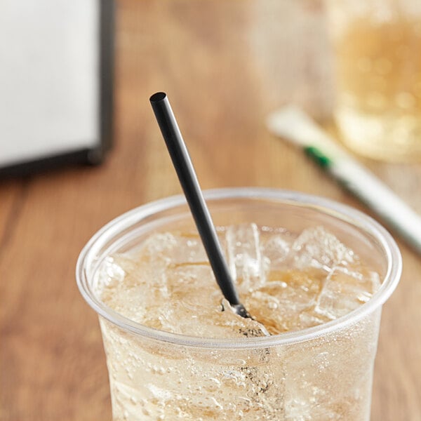 A glass with ice and a EcoChoice Black PLA straw.