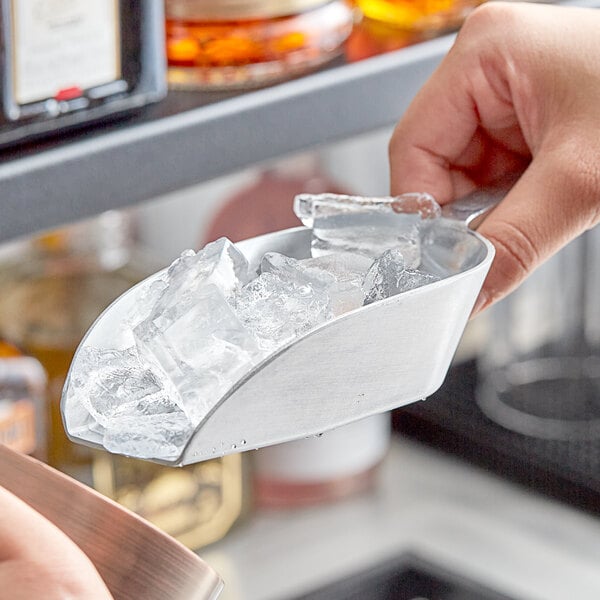 A person holding a Choice aluminum flat bottom scoop of ice.