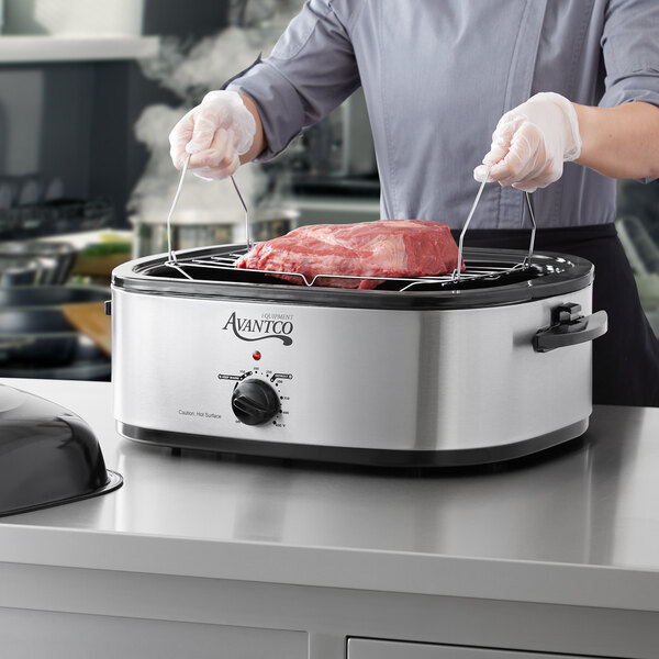 A woman using an Avantco countertop roaster to cook meat.