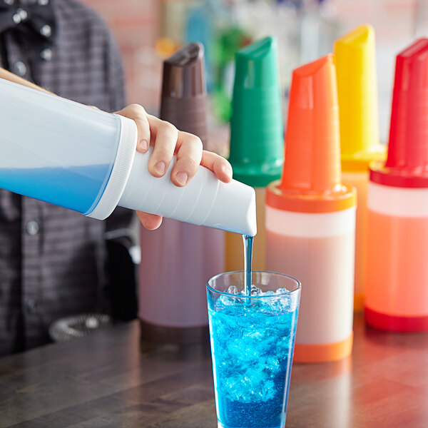 A person using a white and blue Tablecraft PourMaster to pour a blue drink into a glass.