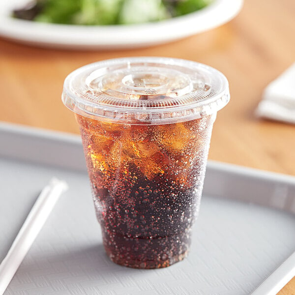 A Choice clear plastic cup with a drink and straw on a tray.