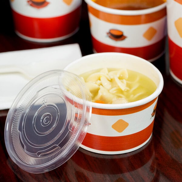 A white paper cup filled with noodle soup and topped with a red and white plastic lid.