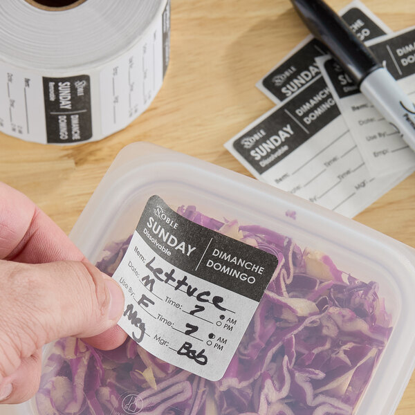 A roll of removable day of the week labels being used to mark a food storage container.